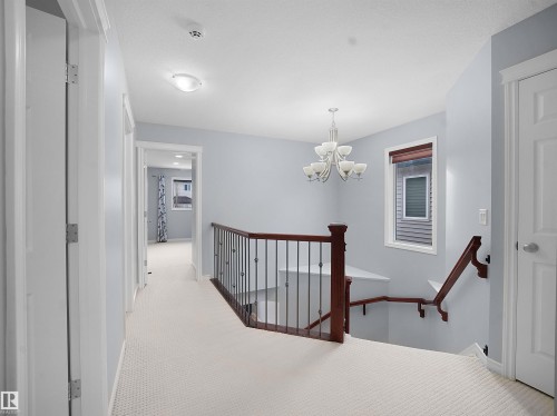 Hall featuring carpet, hanging lights, and an upstairs landing - 6115 11 Avenue, Edmonton, AB - Indoor Photo Showing Other Room