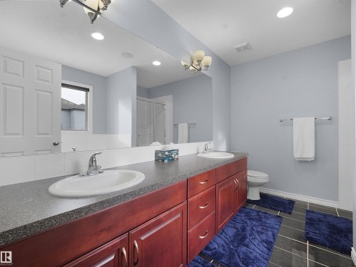 Bathroom featuring a shower stall, double vanity, dark tile patterned flooring, and hanging lights - 6115 11 Avenue, Edmonton, AB - Indoor Photo Showing Bathroom