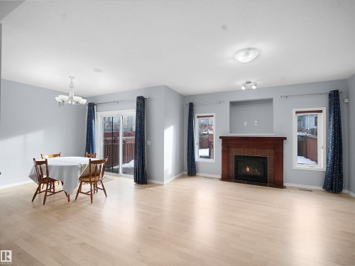 Dining area featuring light wood-style floors, a chandelier, and a fireplace - 6115 11 Avenue, Edmonton, AB - Indoor With Fireplace