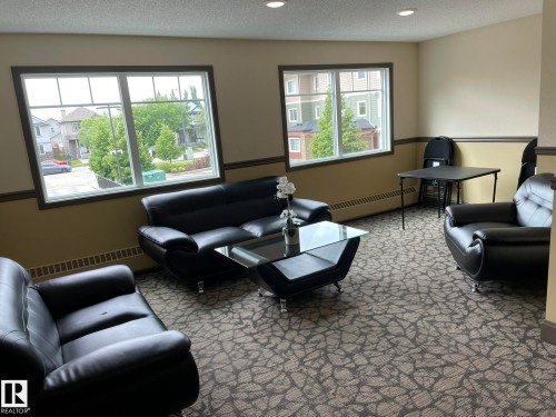Living room featuring baseboard heating, a textured ceiling, light carpet, and recessed lighting - 207 7021 South Terwillegar Drive, Edmonton, AB - Indoor Photo Showing Living Room