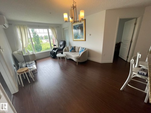 Sitting room with a textured ceiling, dark wood-style flooring, and a chandelier - 207 7021 South Terwillegar Drive, Edmonton, AB - Indoor Photo Showing Living Room