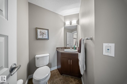 Half bath featuring vanity, a textured ceiling, and dark tile patterned flooring - 8107 224 Street Nw, Edmonton, AB - Indoor Photo Showing Bathroom