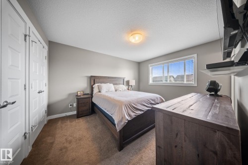 Bedroom featuring dark carpet, a textured ceiling, and a closet - 8107 224 Street Nw, Edmonton, AB - Indoor Photo Showing Bedroom