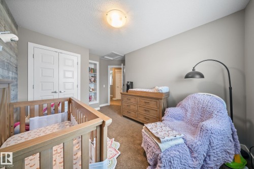 Bedroom featuring a closet, carpet floors, a textured ceiling, and a crib - 8107 224 Street Nw, Edmonton, AB - Indoor Photo Showing Bedroom