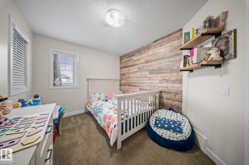 Bedroom featuring wooden walls, dark colored carpet, a textured ceiling, and an accent wall - 8107 224 Street Nw, Edmonton, AB - Indoor Photo Showing Bedroom
