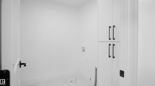 Laundry area with cabinet space, washer hookup, and light marble finish flooring - 711 31 Avenue, Edmonton, AB - Indoor Photo Showing Other Room