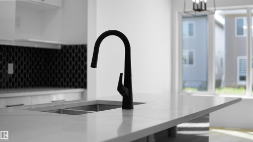 Kitchen view of light stone countertops, decorative backsplash, and white cabinetry - 711 31 Avenue, Edmonton, AB - Indoor