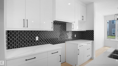 Kitchen featuring white cabinetry, light stone counters, tasteful backsplash, and modern cabinets - 711 31 Avenue, Edmonton, AB - Indoor Photo Showing Kitchen