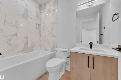 Bathroom featuring vanity, bathtub / shower combination, and light wood finished floors - 9531/ 9533 115 Ave, Edmonton, AB - Indoor Photo Showing Bathroom