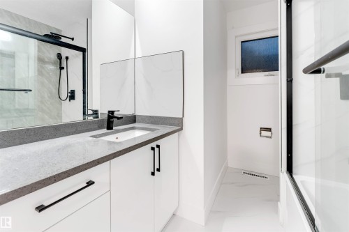 Full bath featuring vanity, light marble finish flooring, and shower / bath combination with glass door - 7303 130 Avenue, Edmonton, AB - Indoor Photo Showing Bathroom