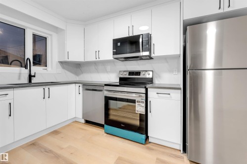 Kitchen with stainless steel appliances, white cabinetry, and light wood-style floors - 7303 130 Avenue, Edmonton, AB - Indoor Photo Showing Kitchen With Upgraded Kitchen