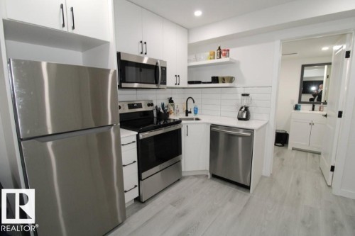 Kitchen featuring stainless steel appliances, white cabinetry, open shelves, backsplash, and light wood finished floors - 22140 81 Avenue, Edmonton, AB - Indoor Photo Showing Kitchen With Upgraded Kitchen
