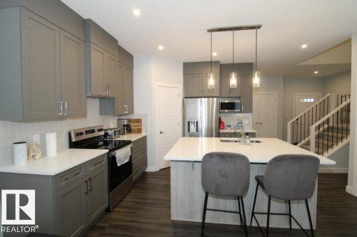 Kitchen featuring gray cabinets, stainless steel appliances, tasteful backsplash, a kitchen island with sink, and hanging light fixtures - 22140 81 Avenue, Edmonton, AB - Indoor Photo Showing Kitchen With Double Sink With Upgraded Kitchen