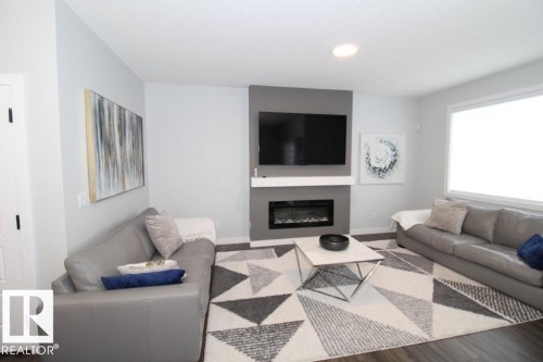 Living room with a glass covered fireplace, wood finished floors, and recessed lighting - 22140 81 Avenue, Edmonton, AB - Indoor Photo Showing Living Room With Fireplace
