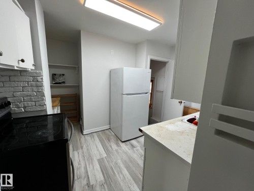 Kitchen featuring electric stove, white cabinetry, freestanding refrigerator, light countertops, and light wood-style floors - 10830 68 Avenue, Edmonton, AB - Indoor Photo Showing Kitchen