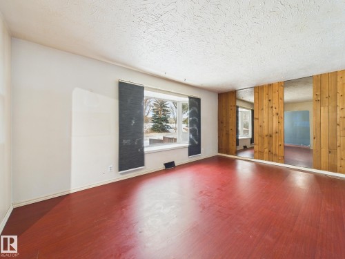 Empty room with wooden walls, wood finished floors, and a textured ceiling - 13523 124B Avenue, Edmonton, AB - Indoor Photo Showing Other Room
