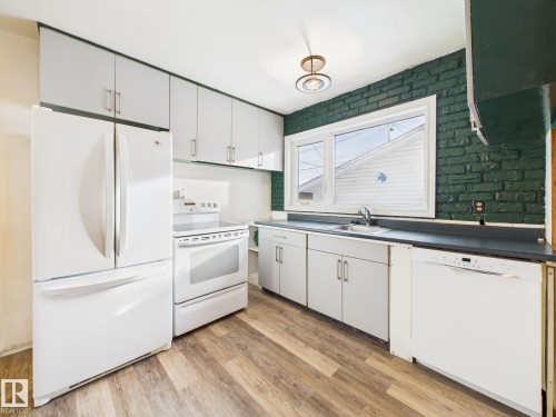 Kitchen featuring white appliances, white cabinetry, light wood-style floors, and dark countertops - 13523 124B Avenue, Edmonton, AB - Indoor Photo Showing Kitchen
