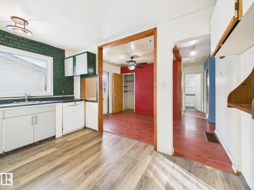 Kitchen with white cabinetry, dark countertops, dishwasher, light wood-style flooring, and ceiling fan - 13523 124B Avenue, Edmonton, AB - Indoor Photo Showing Kitchen