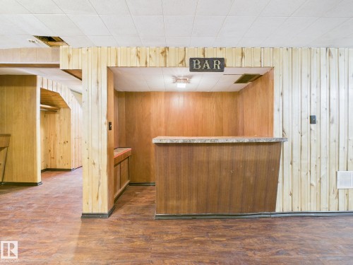Indoor dry bar featuring light countertops, dark wood finished floors, wooden walls, and wood finish cabinetry - 13523 124B Avenue, Edmonton, AB - Indoor Photo Showing Other Room