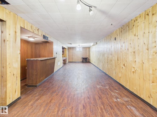 Finished basement with dark wood-style floors, a dry bar, track lighting, and wood walls - 13523 124B Avenue, Edmonton, AB - Indoor Photo Showing Other Room