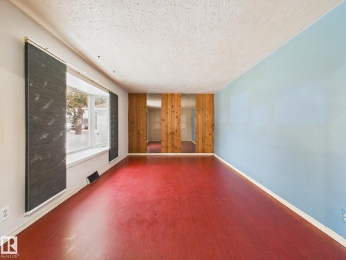 Spare room with wood finished floors, wooden walls, and a textured ceiling - 13523 124B Avenue, Edmonton, AB - Indoor Photo Showing Other Room