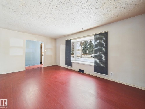 Empty room with arched walkways, wood finished floors, and a textured ceiling - 13523 124B Avenue, Edmonton, AB - Indoor Photo Showing Other Room