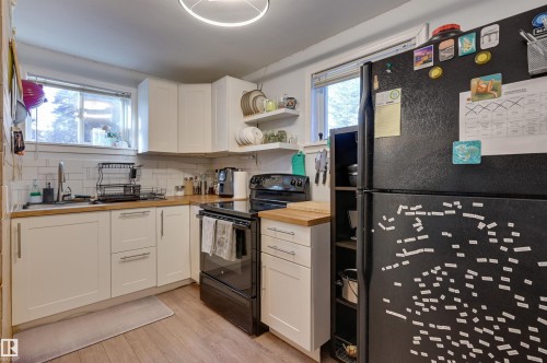 Kitchen with black appliances, white cabinetry, open shelves, butcher block countertops, and light wood-style flooring - 10911 66 Avenue, Edmonton, AB - Indoor Photo Showing Kitchen