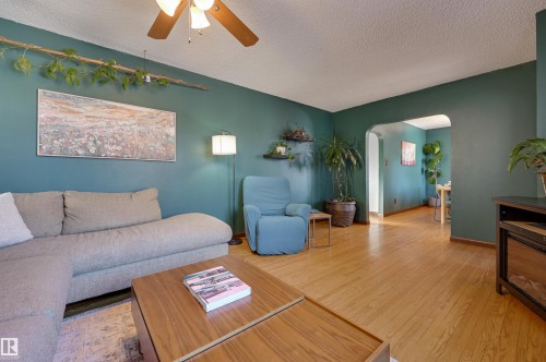 Living area featuring arched walkways, a ceiling fan, wood-type flooring, and a textured ceiling - 10911 66 Avenue, Edmonton, AB - Indoor Photo Showing Living Room