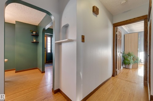 Hallway featuring a textured ceiling, light wood finished floors, and arched walkways - 10911 66 Avenue, Edmonton, AB - Indoor Photo Showing Other Room