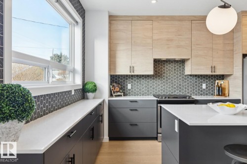 Dual tone kitchen with stainless steel range with electric cooktop, modern cabinets, light stone countertops, light wood-type flooring, and two tone cabinets - 11016 132 Street, Edmonton, AB - Indoor Photo Showing Kitchen With Upgraded Kitchen
