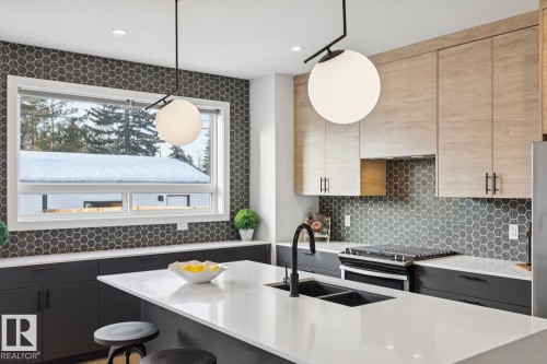 Kitchen featuring a kitchen bar, stainless steel gas range oven, light stone countertops, pendant lighting, and tasteful backsplash - 11016 132 Street, Edmonton, AB - Indoor Photo Showing Kitchen With Double Sink With Upgraded Kitchen