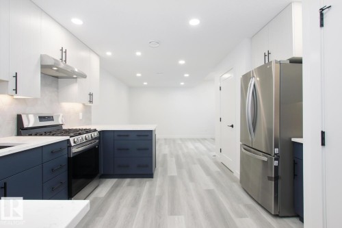 Dual tone kitchen with two tone cabinets, stainless steel appliances, light wood-style flooring, a peninsula, and tasteful backsplash - 11016 132 Street, Edmonton, AB - Indoor Photo Showing Kitchen With Upgraded Kitchen
