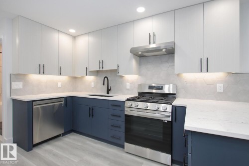Kitchen with stainless steel appliances, dual tone cabinetry, light stone countertops, backsplash, and light wood-type flooring - 11016 132 Street, Edmonton, AB - Indoor Photo Showing Kitchen With Upgraded Kitchen