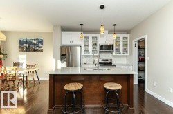 Kitchen featuring glass fronted cabinets, stainless steel appliances, a kitchen breakfast bar, and white cabinets - 