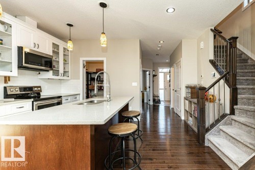 Kitchen featuring stainless steel appliances, glass insert cabinets, decorative light fixtures, a kitchen bar, and dark wood-style flooring - 10535 67 Avenue, Edmonton, AB - Indoor Photo Showing Kitchen With Double Sink With Upgraded Kitchen