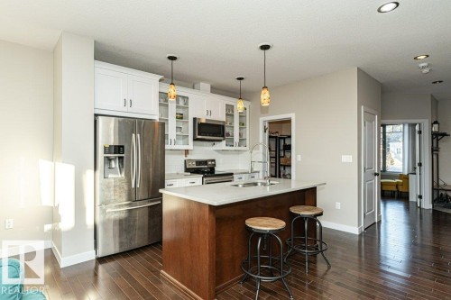 Kitchen featuring stainless steel appliances, hanging light fixtures, glass fronted cabinets, a kitchen breakfast bar, and a center island with sink - 10535 67 Avenue, Edmonton, AB - Indoor Photo Showing Kitchen With Stainless Steel Kitchen With Upgraded Kitchen