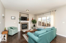 Living area featuring dark wood-type flooring, a stone fireplace, and a textured ceiling - 