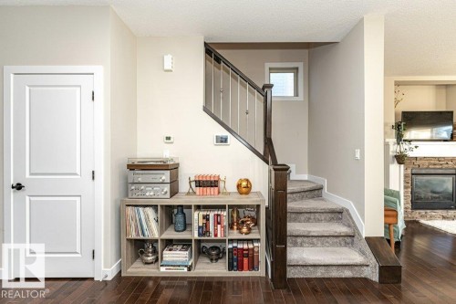 Stairs with wood-type flooring, a textured ceiling, and a stone fireplace - 10535 67 Avenue, Edmonton, AB - Indoor Photo Showing Other Room With Fireplace