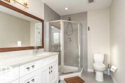 Bathroom with double vanity, a shower stall, light tile patterned floors, and a textured ceiling - 