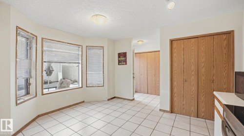 Kitchen with a textured ceiling, black range with electric cooktop, light tile patterned floors, and wood finish cabinets - 1509 Jarvis Cr, Edmonton, AB - Indoor Photo Showing Other Room