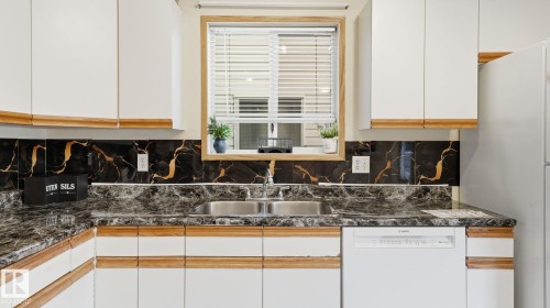 Two tone kitchen with white dishwasher, freestanding refrigerator, tasteful backsplash, and dual tone cabinets - 1509 Jarvis Cr, Edmonton, AB - Indoor Photo Showing Kitchen With Double Sink