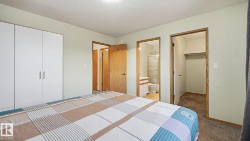 Carpeted bedroom featuring a textured ceiling and connected bathroom - 1509 Jarvis Cr, Edmonton, AB - Indoor Photo Showing Bedroom