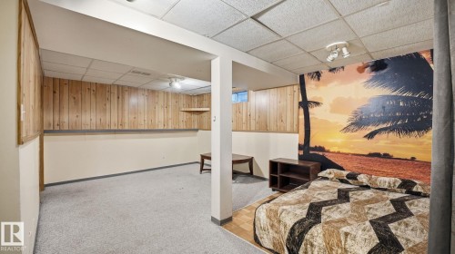 Bedroom featuring a paneled ceiling, wood walls, light carpet, and parquet floors - 1509 Jarvis Cr, Edmonton, AB - Indoor
