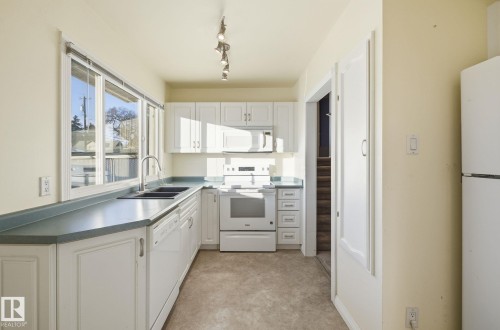 Kitchen with white appliances and white cabinets - 12916 95A Street, Edmonton, AB - Indoor Photo Showing Kitchen With Double Sink