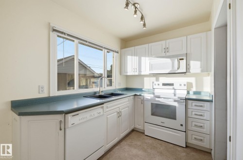 Kitchen featuring white appliances and white cabinets - 12916 95A Street, Edmonton, AB - Indoor Photo Showing Kitchen With Double Sink
