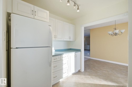 Kitchen with freestanding refrigerator, white cabinetry, and a chandelier - 12916 95A Street, Edmonton, AB - Indoor Photo Showing Kitchen