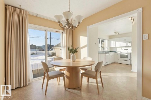 The dining area features a chandelier light fixture and sliding glass doors, offering views of the exterior - 12916 95A Street, Edmonton, AB - Indoor Photo Showing Dining Room