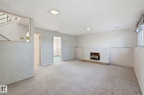 Basement featuring carpet flooring and a fireplace with raised hearth - 12916 95A Street, Edmonton, AB - Indoor