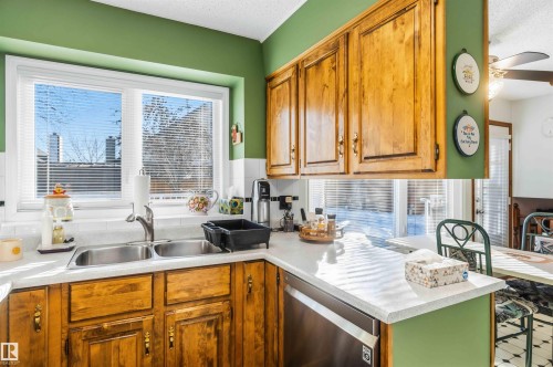 Kitchen with stainless steel dishwasher, plenty of natural light, wood finish cabinets, light countertops, and a textured ceiling - 17619 94 Ave, Edmonton, AB - Indoor Photo Showing Kitchen With Double Sink