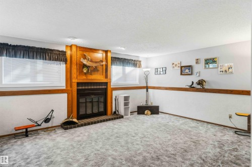Living room featuring a textured ceiling, carpet floors, and a large fireplace - 17619 94 Ave, Edmonton, AB - Indoor Photo Showing Other Room With Fireplace